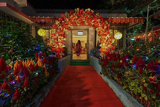 A lady strolls under a perfectly lit passage embellished with red and white blossoms, prompting an enticing entry, part of the happy stylistic layout at Khelaghar Baganbari.